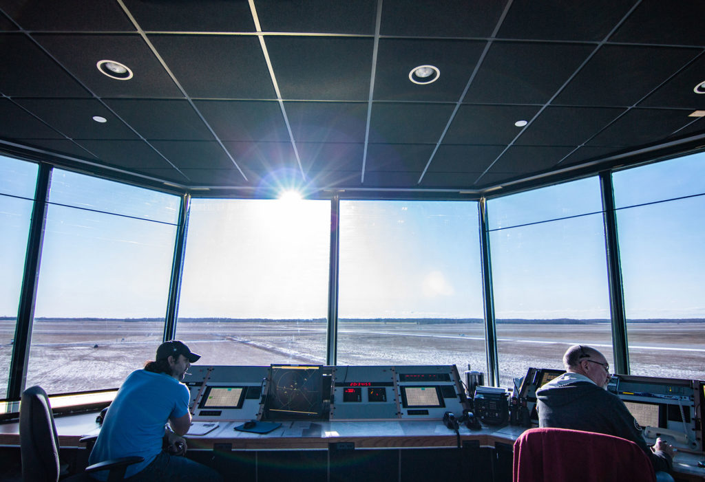 Employees working in an air traffic control tower overlooking the runway at CFTS Southport in Manitoba.